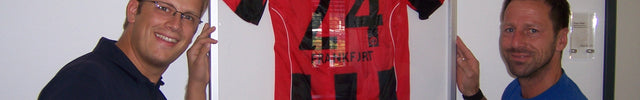 Uwe Bindewald im NLZ von Eintracht Frankfurt vor dem gerahmten Trikot von Sebastian Jung