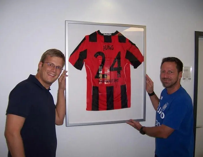 Uwe Bindewald vor Trikotrahmen im Sportleistungszentrum von Eintracht Frankfurt