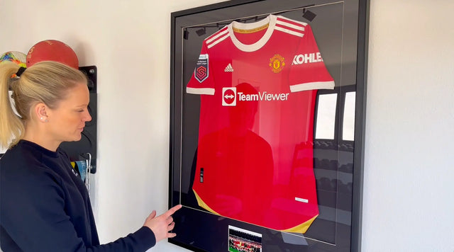 Diane Caldwell zeigt auf ihr gerahmtes Manchester United Frauen-Trikot aus der Women's Super League 2021.
