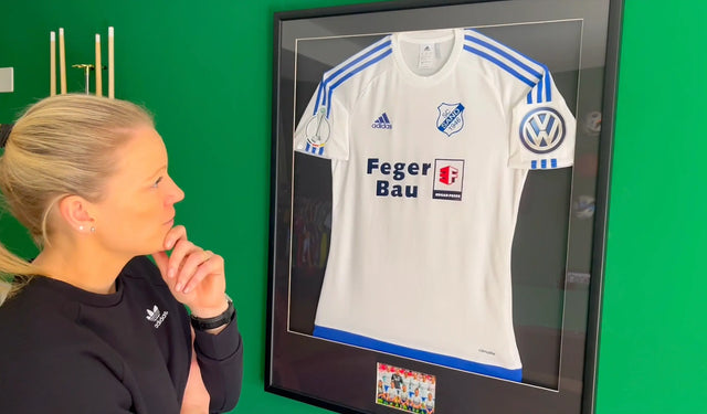 Diane Caldwell betrachtet nachdenklich ihr gerahmtes Trikot vom DFB-Pokalfinale 2017 zwischen SC Sand und VfL Wolfsburg, ein exklusives Einzelstück nur für dieses Finale.