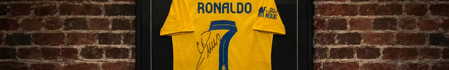 Signiertes Cristiano Ronaldo Trikot von Al-Nassr im Trikotrahmen "Premium Plurs"(Holz) mit Passepartout und Foto – Schwarz-Matt mit schwarzem Hintergrund an Backsteinwand